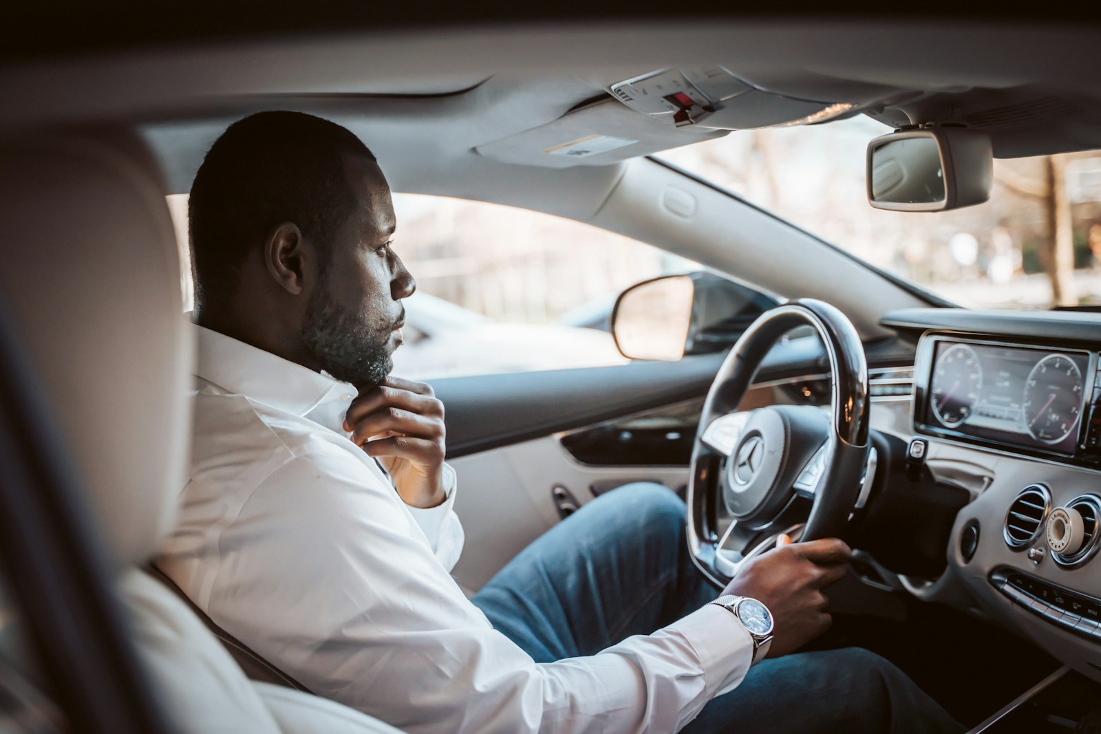 man in white dress shirt driving car during daytime auto