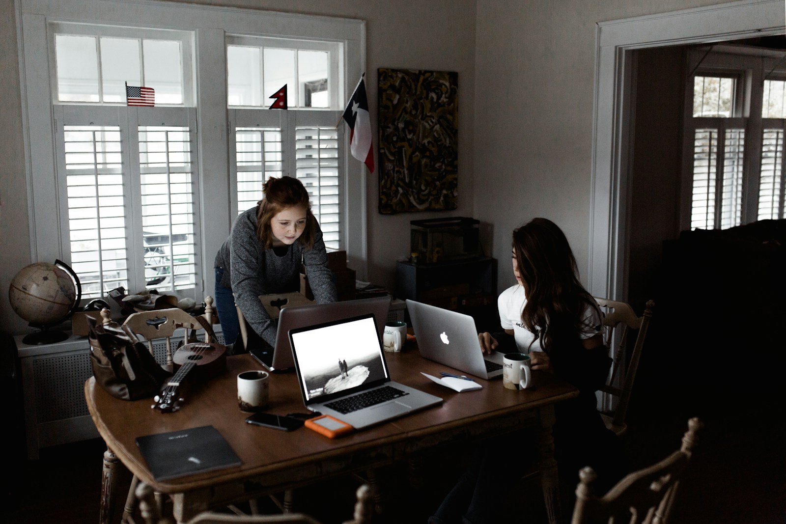 women using laptop on brown wooden table renters